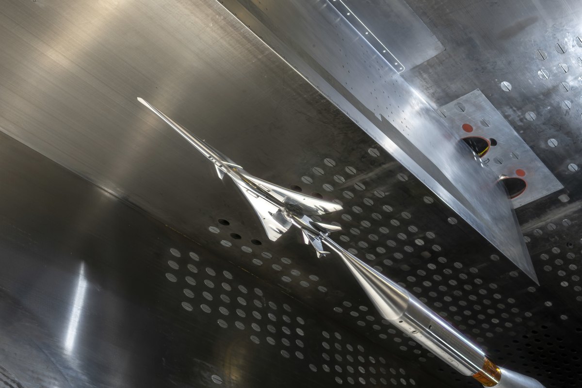 Polished model of a supersonic aircraft on its support inside a perforated-wall wind tunnel